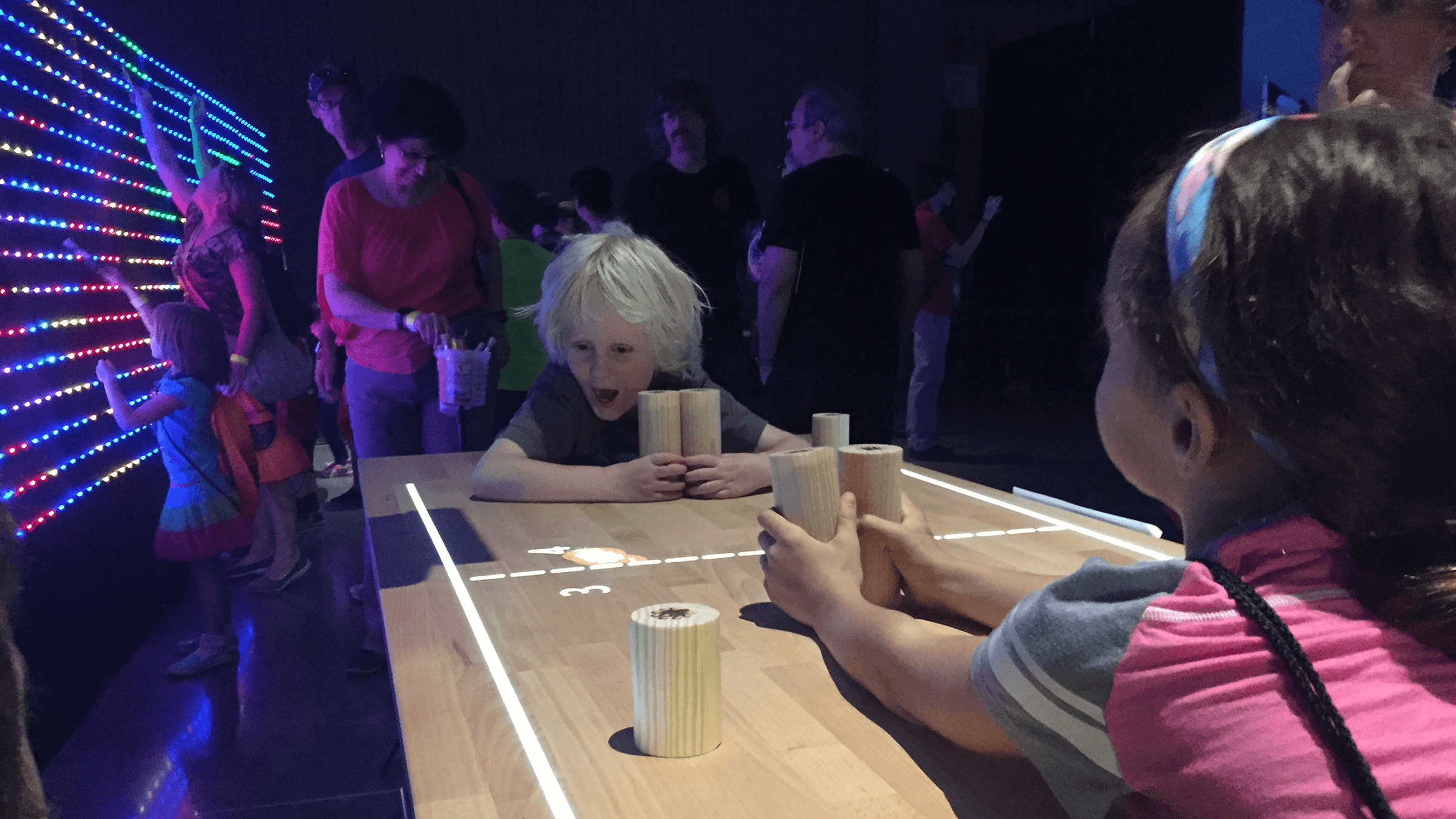 Two children play using interactive light on a wooden table during an event