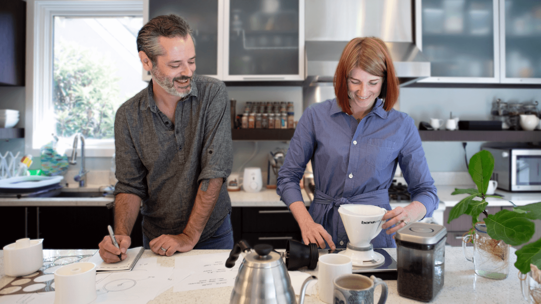 Two people standing in a kitchen, one of them is using the Stäk coffee maker