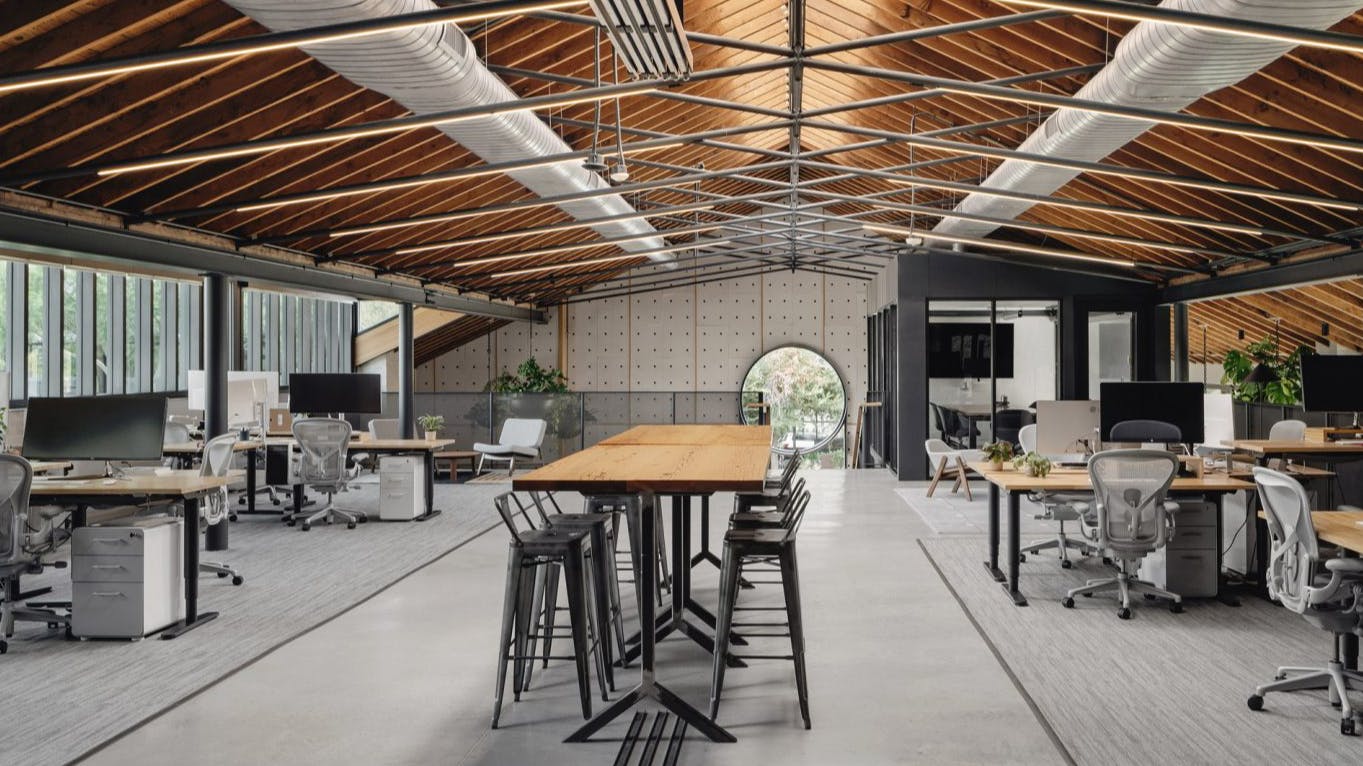 View of an empty argodesign studio with desks and chars, wood panel roof, and a circular window looking out on South Congress.