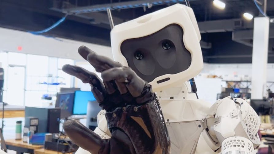 A humanoid robot looking at its hand.